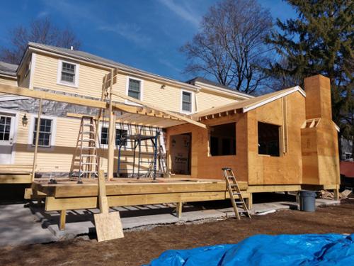 Family room addition off the back of the house with a large deck being framed.